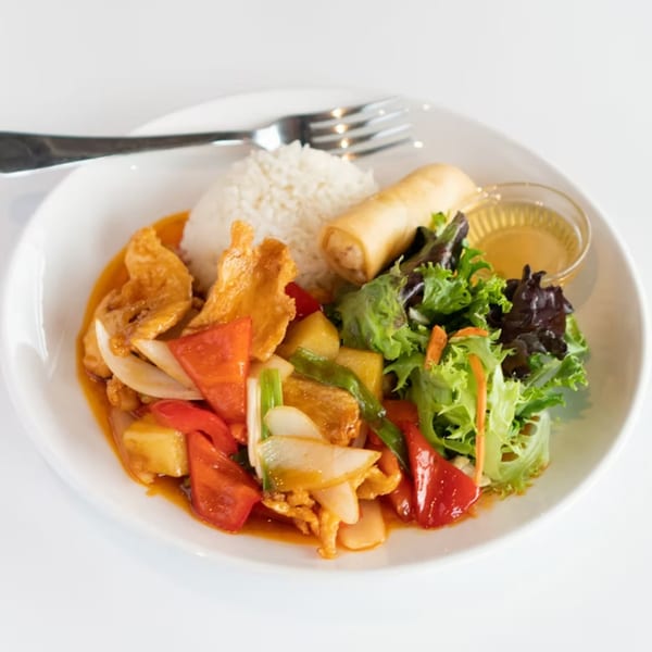 Sweet and sour chicken with rice, spring roll, and salad on a white plate.