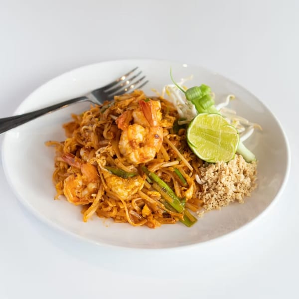 A plate of shrimp Pad Thai with lime, bean sprouts, and crushed peanuts from Rice Fine Thai Cuisine.