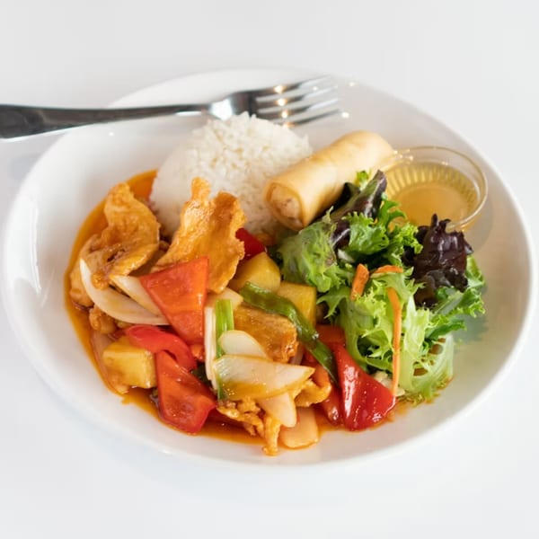 Sweet and sour chicken with rice, spring roll, and salad on a white plate.