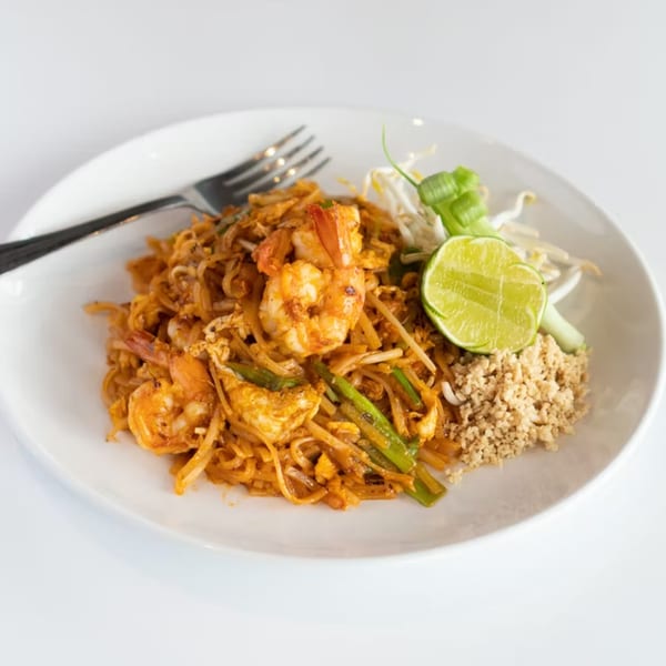 A plate of Rice Fine Thai Cuisine's Pad Thai with shrimp, lime, and crushed peanuts.