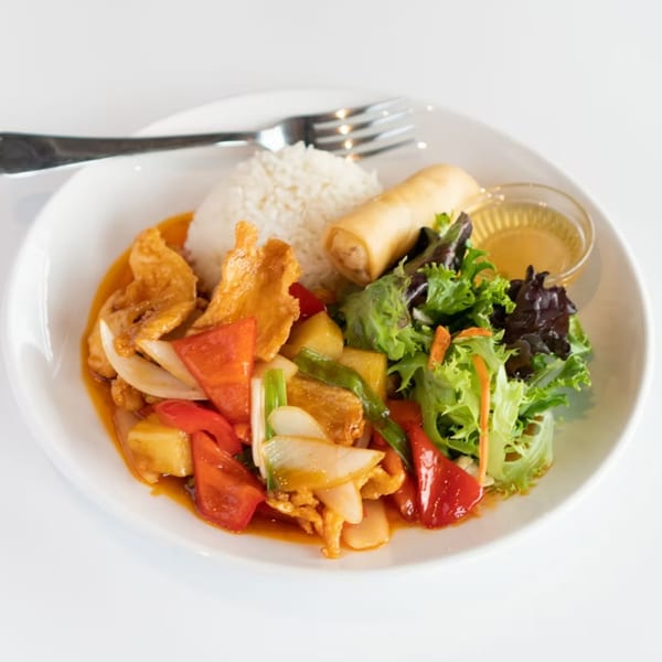 Sweet and sour chicken with rice, an egg roll, and a side salad on a white plate.