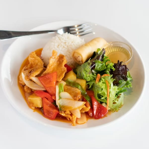 Sweet and sour chicken with rice, egg roll, and salad on a white plate.