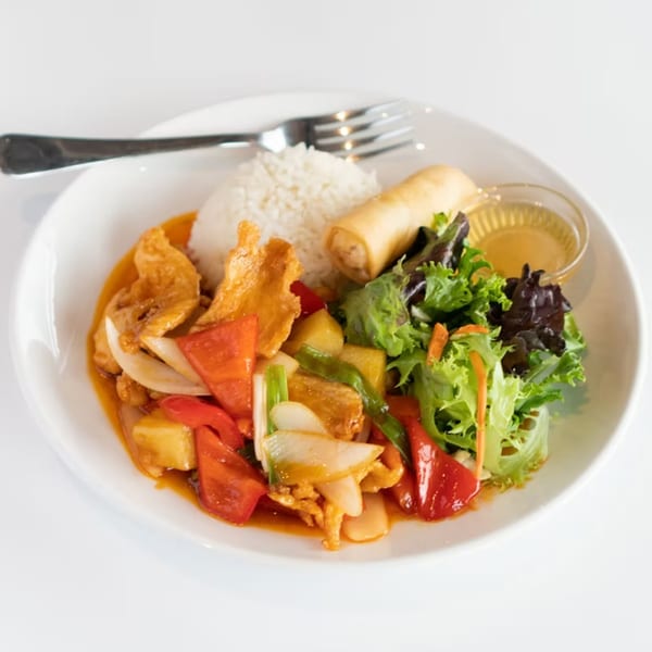 Sweet and sour chicken with rice, spring roll, and salad on a white plate.